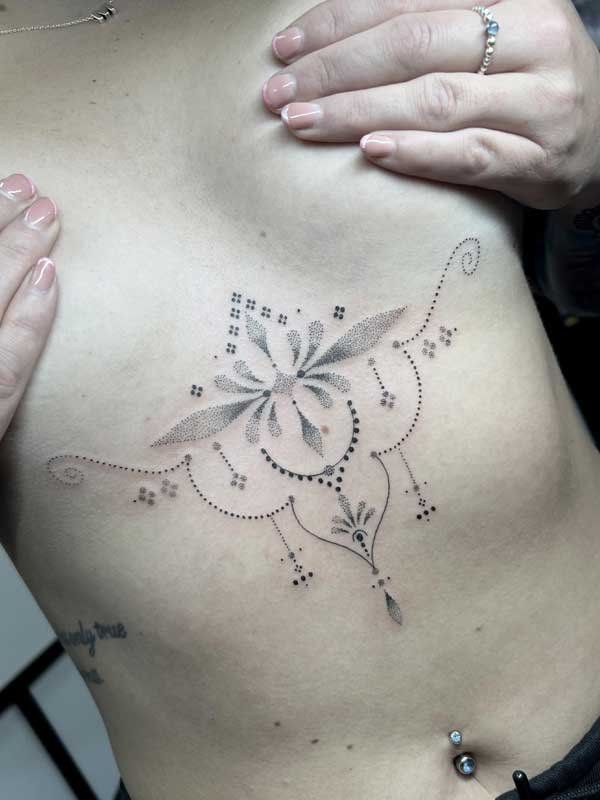 A woman is holding her chest with a tattoo on it.