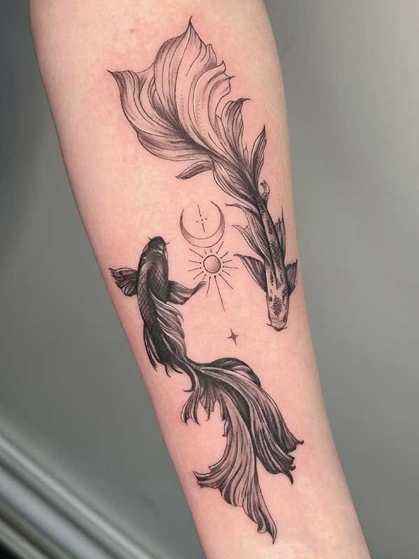 A black and white tattoo of two fish on a person 's forearm.